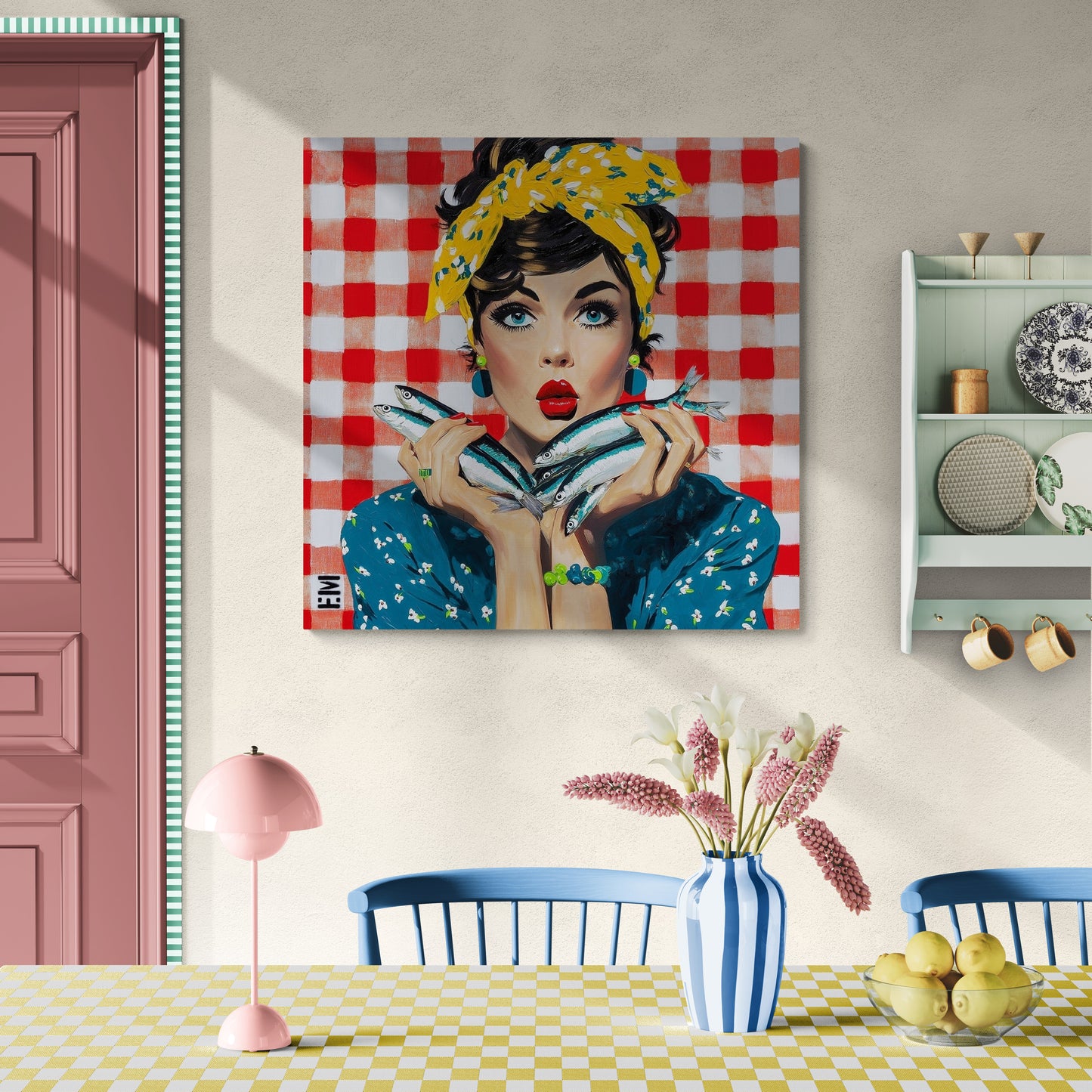 A square canvas wall art print featuring a stylized pop-art portrait of a woman with a yellow floral headband, blue floral blouse, and holding silver fish, set against a red and white gingham background. The canvas is displayed on a beige wall in a styled dining room setting with a pink door, blue chairs, a pink lamp, and a blue-and-white striped vase.