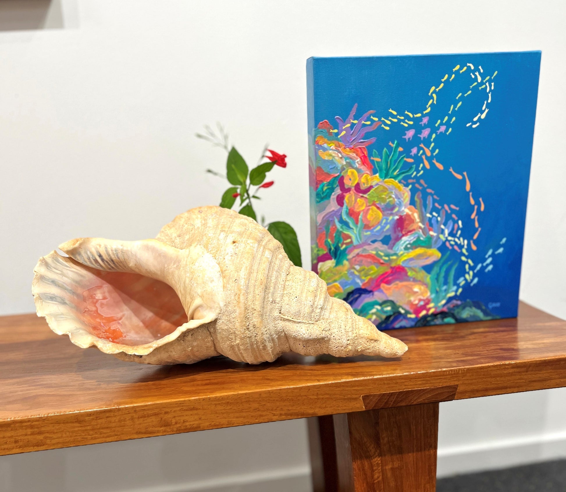 Large shell on a wooden surface with a colorful painting in the background