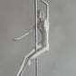 White mannequin of a pole dancer against a gray background