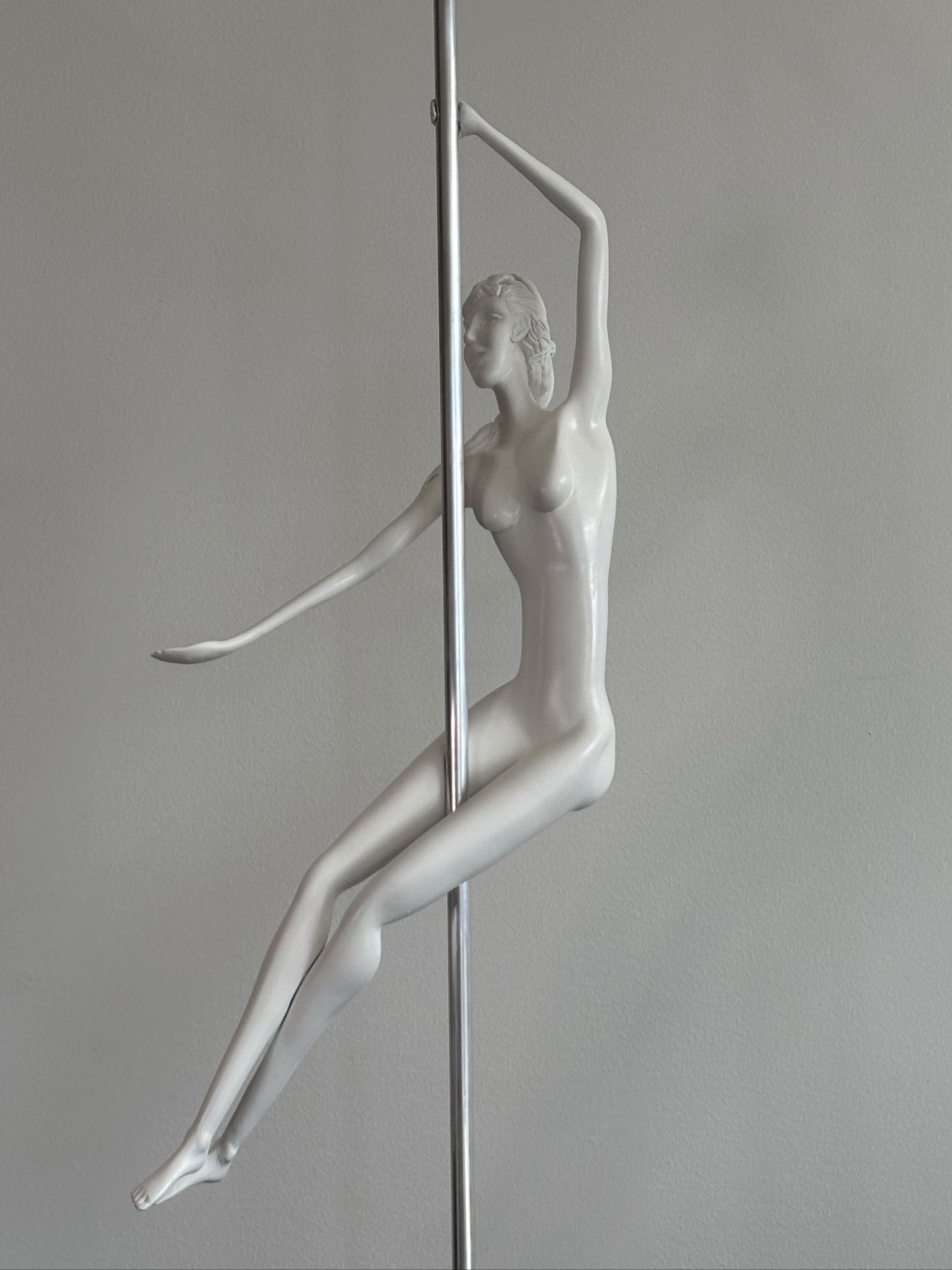 White mannequin of a pole dancer against a gray background