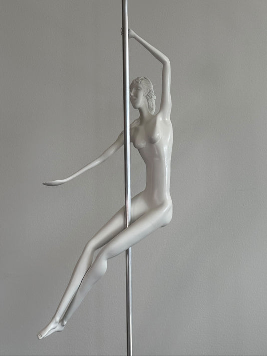 White mannequin of a pole dancer against a gray background