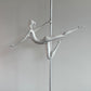 Silver pole dancing sculpture on a wooden base against a plain wall