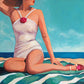 Woman in a white swimsuit with a red flower sitting on a beach.