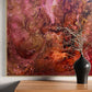 Abstract art piece with pink and brown colors on a wall above a wooden console table with a black vase.