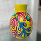 Colorful hand-painted vase with abstract patterns on a white background